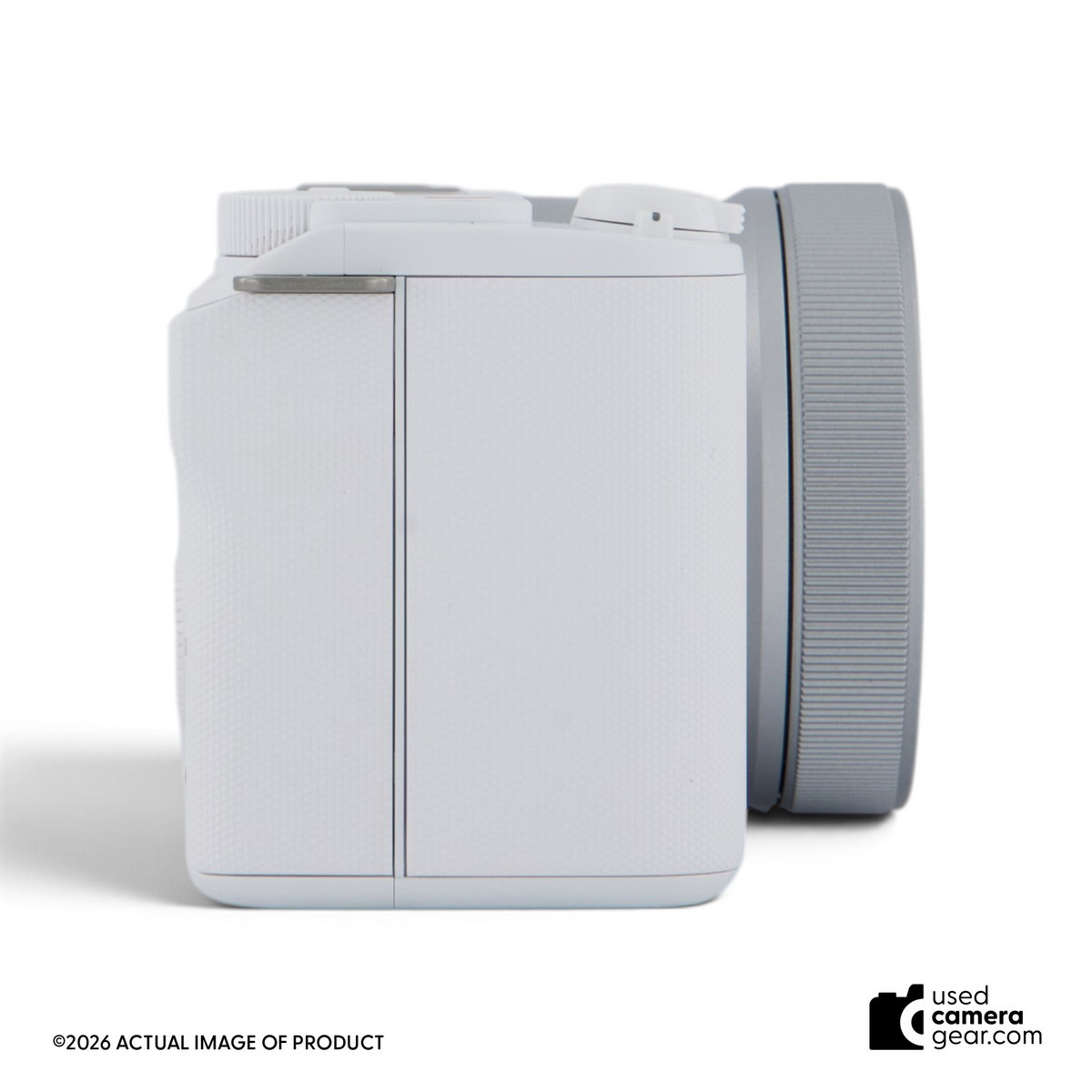 Usedcameragear white Sony ZV-E10 II mirrorless camera with 16-50mm lens, side view showing compact body design.